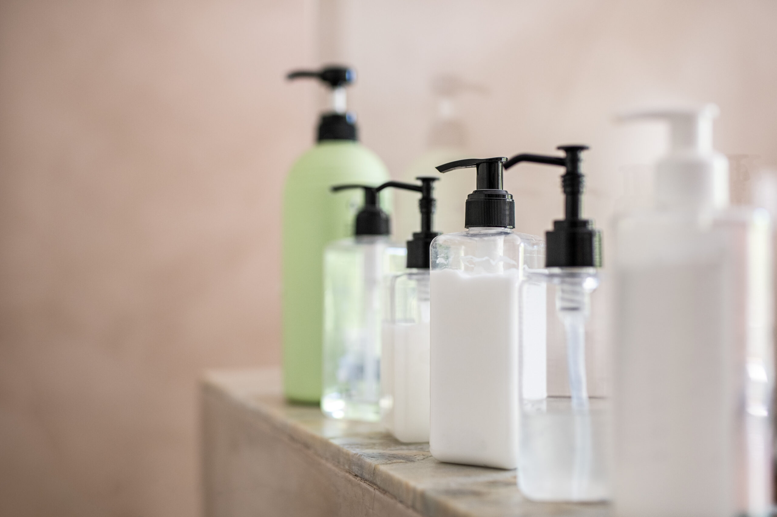 Different face wash and serum bottles on a clean vanity table